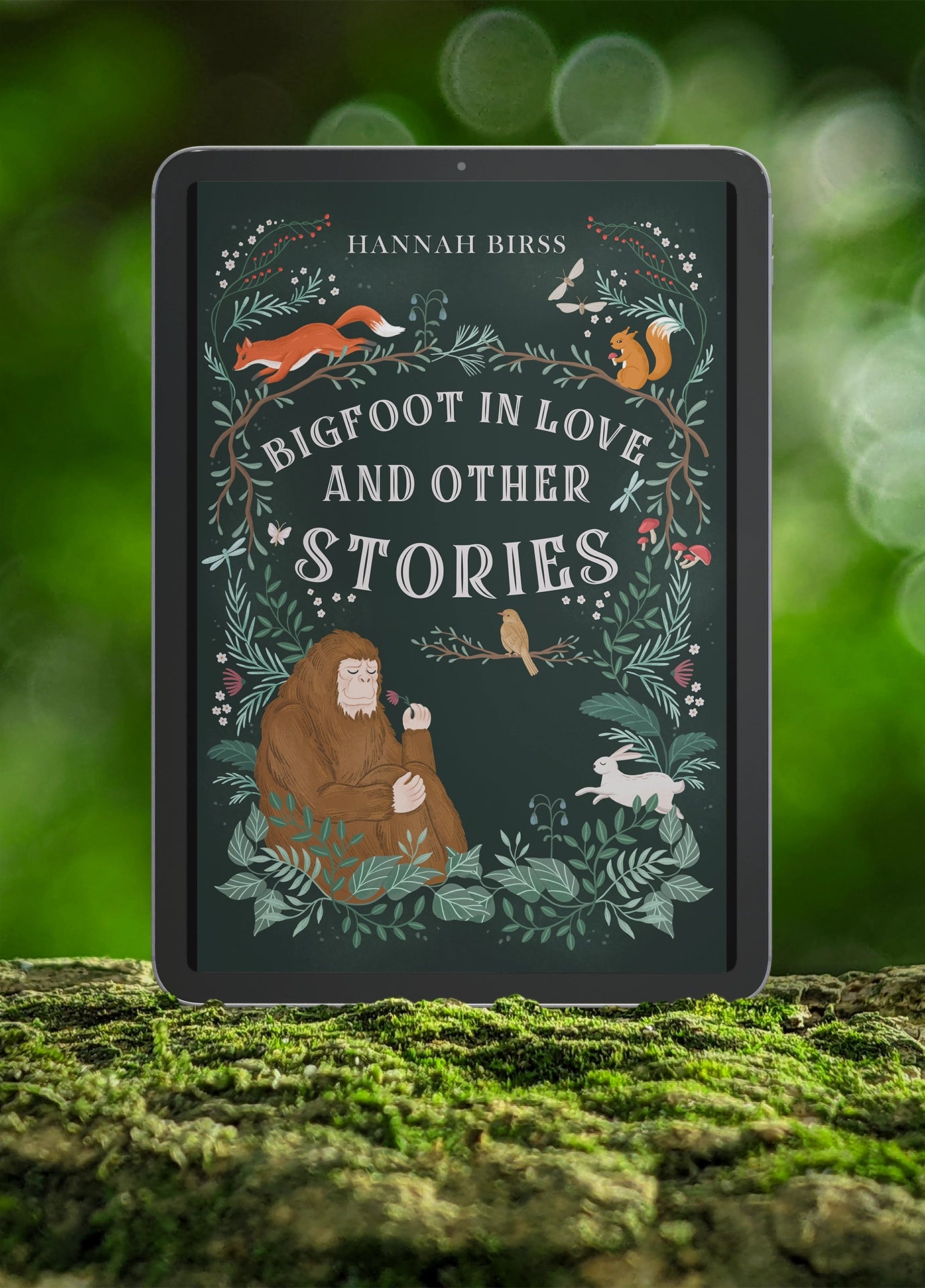 Book cover of "Bigfoot in Love and Other Stories" by Hannah Birss displayed on a tablet on a bed of moss in a forest.
